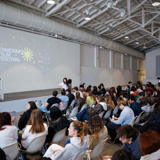 Ambiente di auditorium con pubblico seduto, pavimento in gres porcellanato chiaro, superficie liscia e finitura opaca.